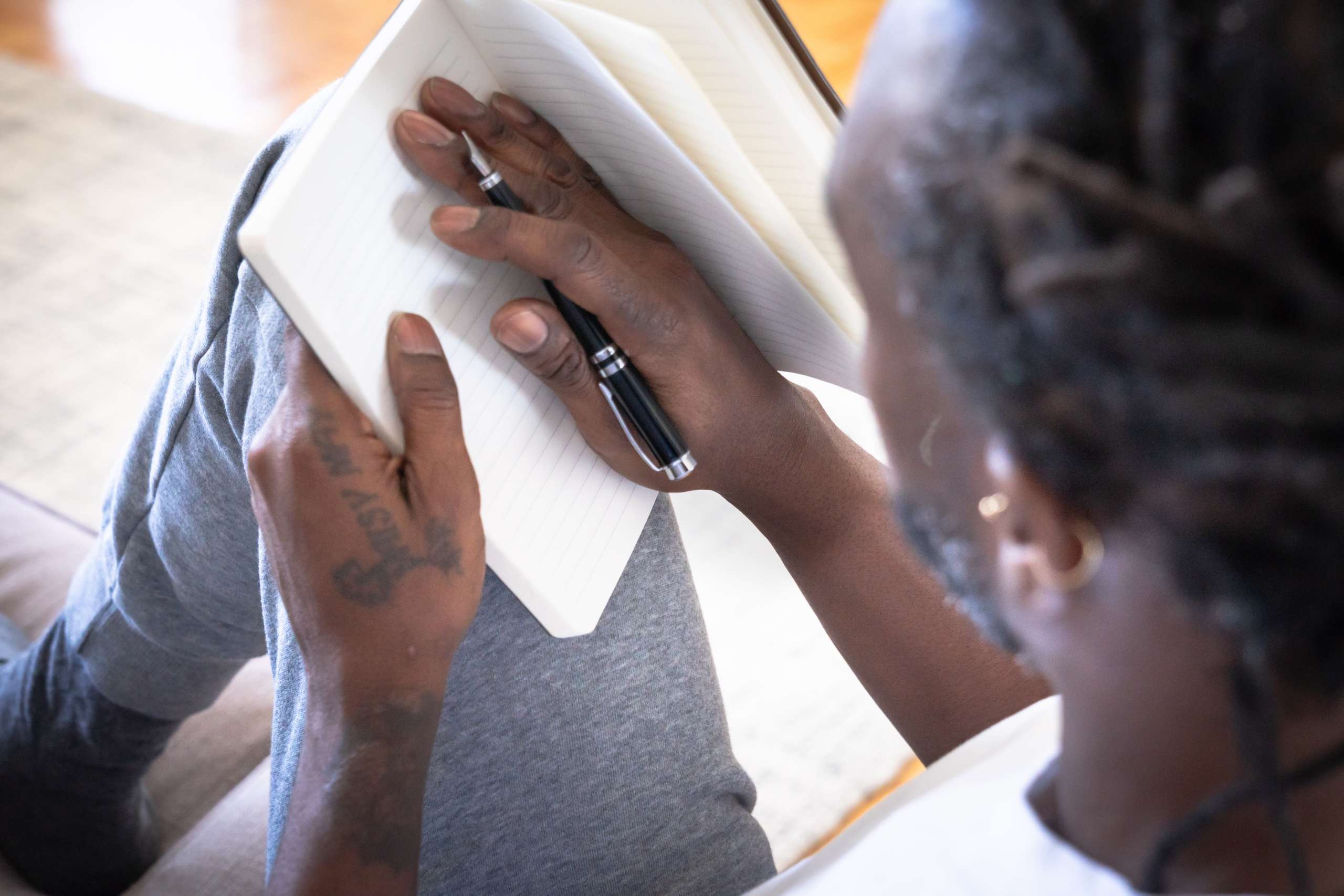 man writing in notebook journaling